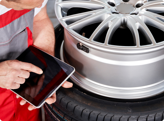 Commercial tire technician using a tablet next to a truck wheel